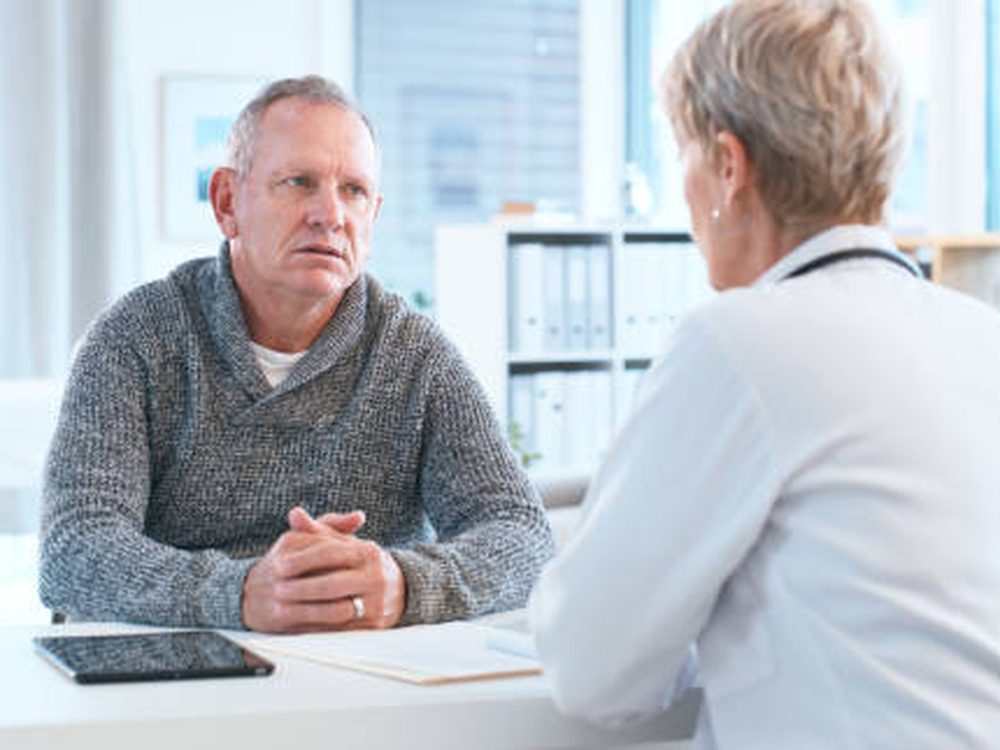 A doctor in friendly conversation with a patient in a bright clinic
